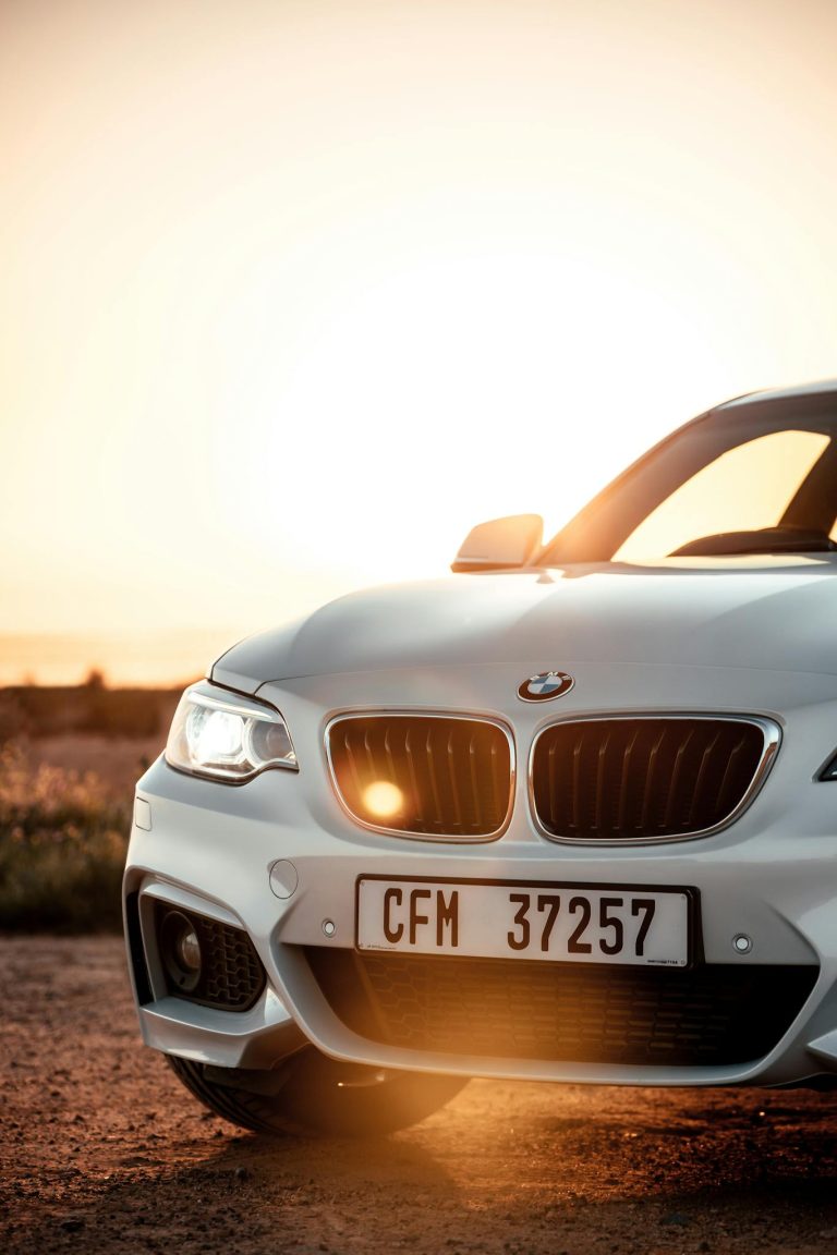 Captivating shot of a white BMW coupe at sunset on a scenic road in Cape Town, South Africa.
